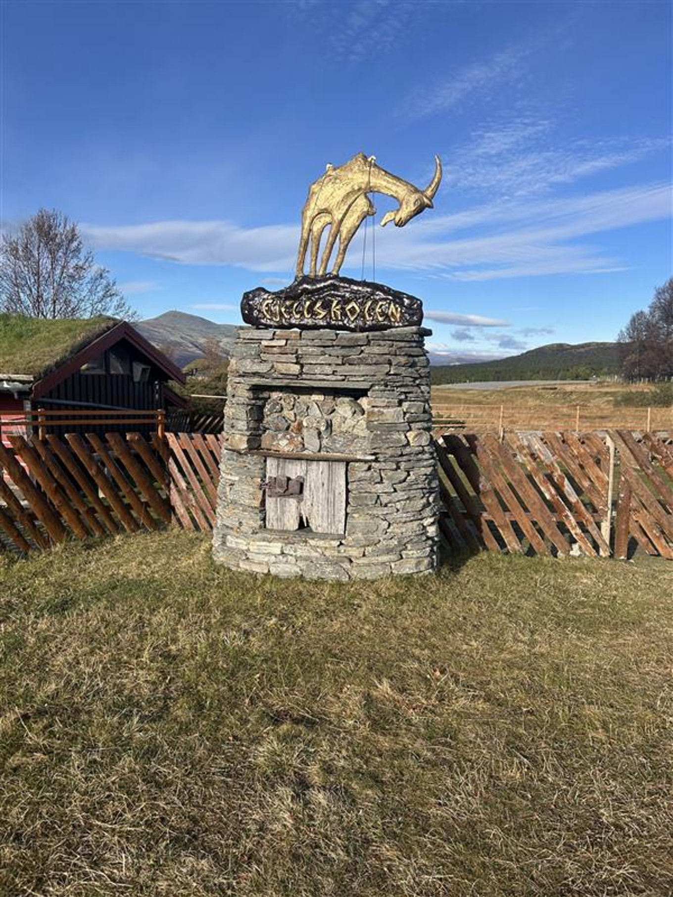 En statue av en hjort på en steinstruktur på et jorde En statue av en hjort på en steinstruktur på et jorde