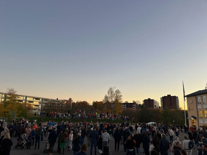 En mengde mennesker utenfor en skole i kveldsstemning