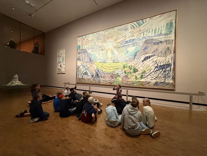 en gruppe mennesker som sitter foran et maleri av Munch