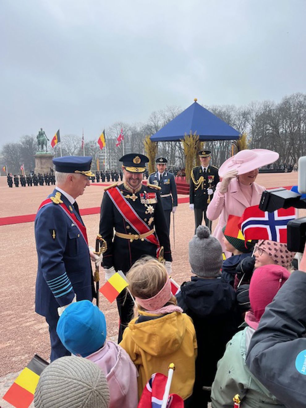 en gruppe mennesker som står på fortauet