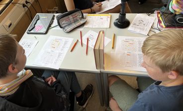 en gruppe mennesker som sitter rundt et bord med papirer og blyanter