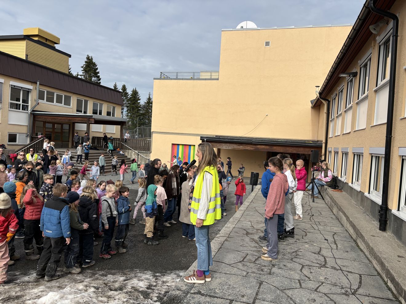 en gruppe mennesker som står utenfor en skole