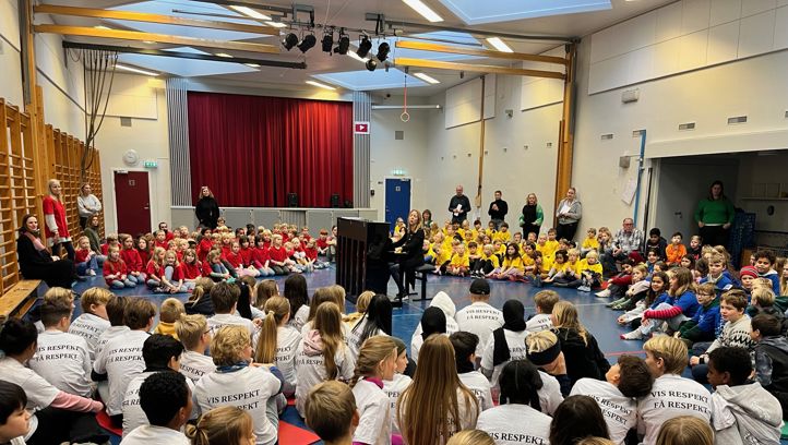 skoleelever synger og lærer som spiller piano