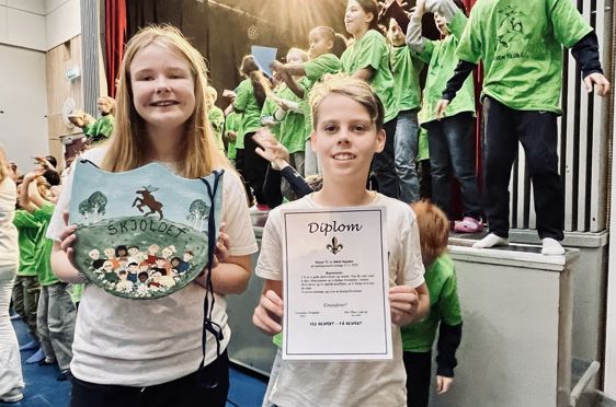 To barn som holder skilt og diplom