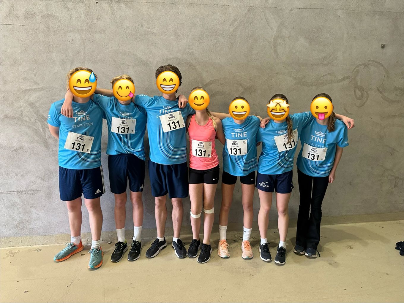 En gruppe mennesker iført nummer og stående foran en vegg